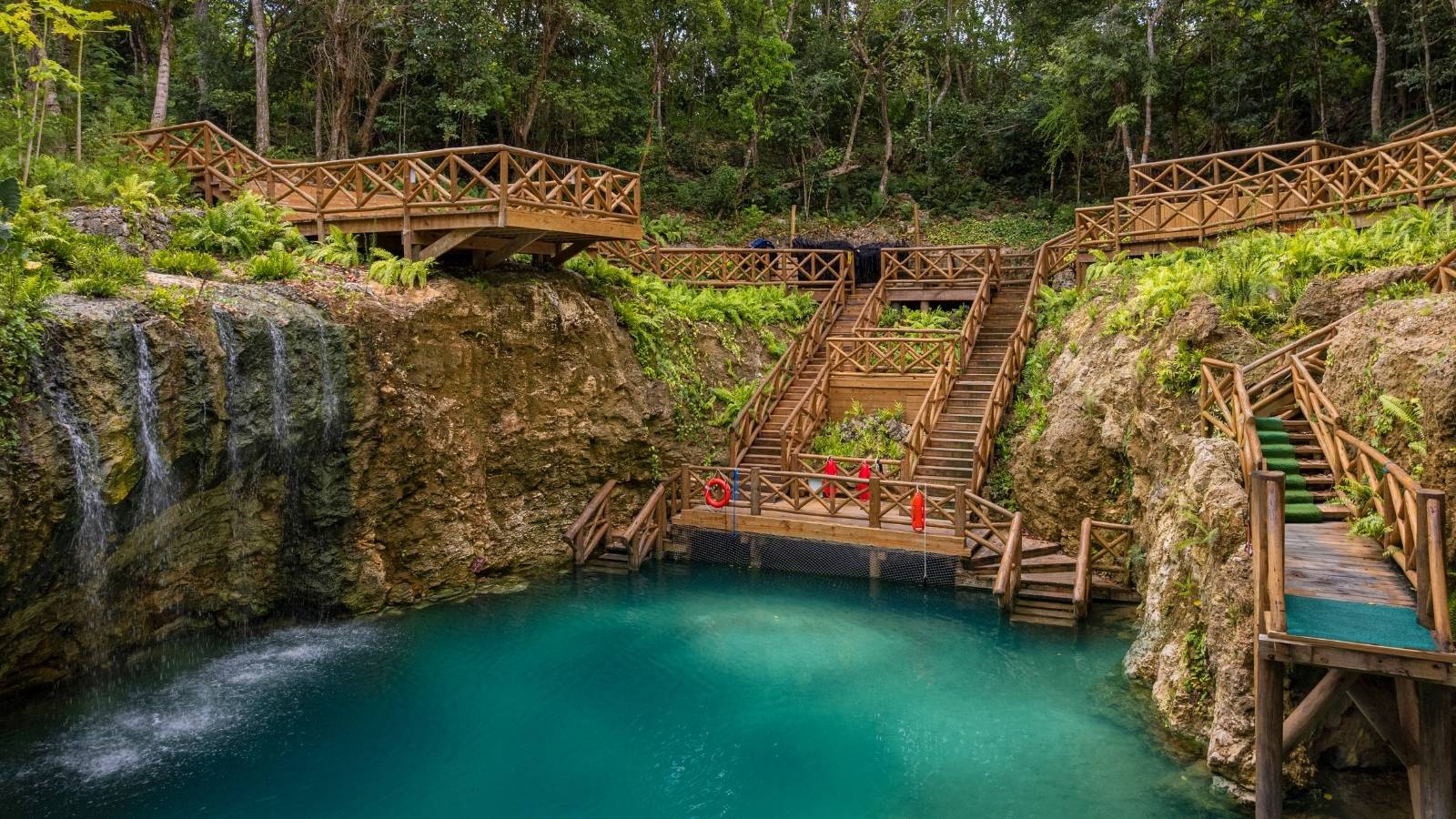 Blue Hole cenote with waterfalls and wooden stairs at Scape Park, Cap Cana